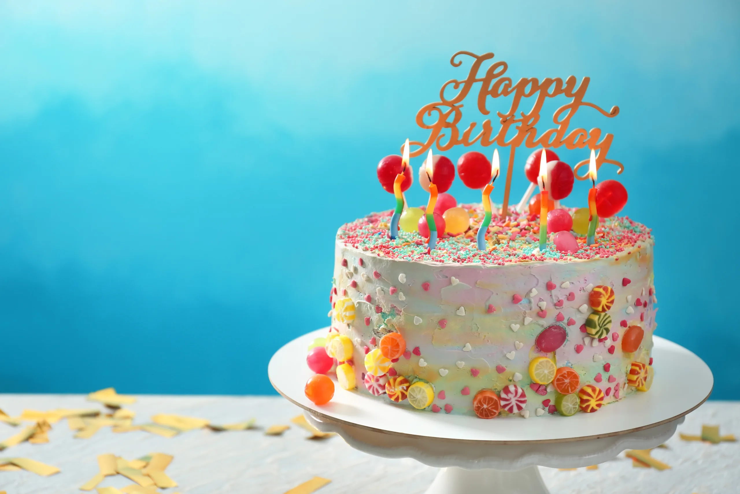 Stand with beautiful tasty birthday cake on table against color background